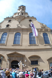 Die Heilig Kreuz Kirche mit ihrer Gemeinde und Friedenstauben